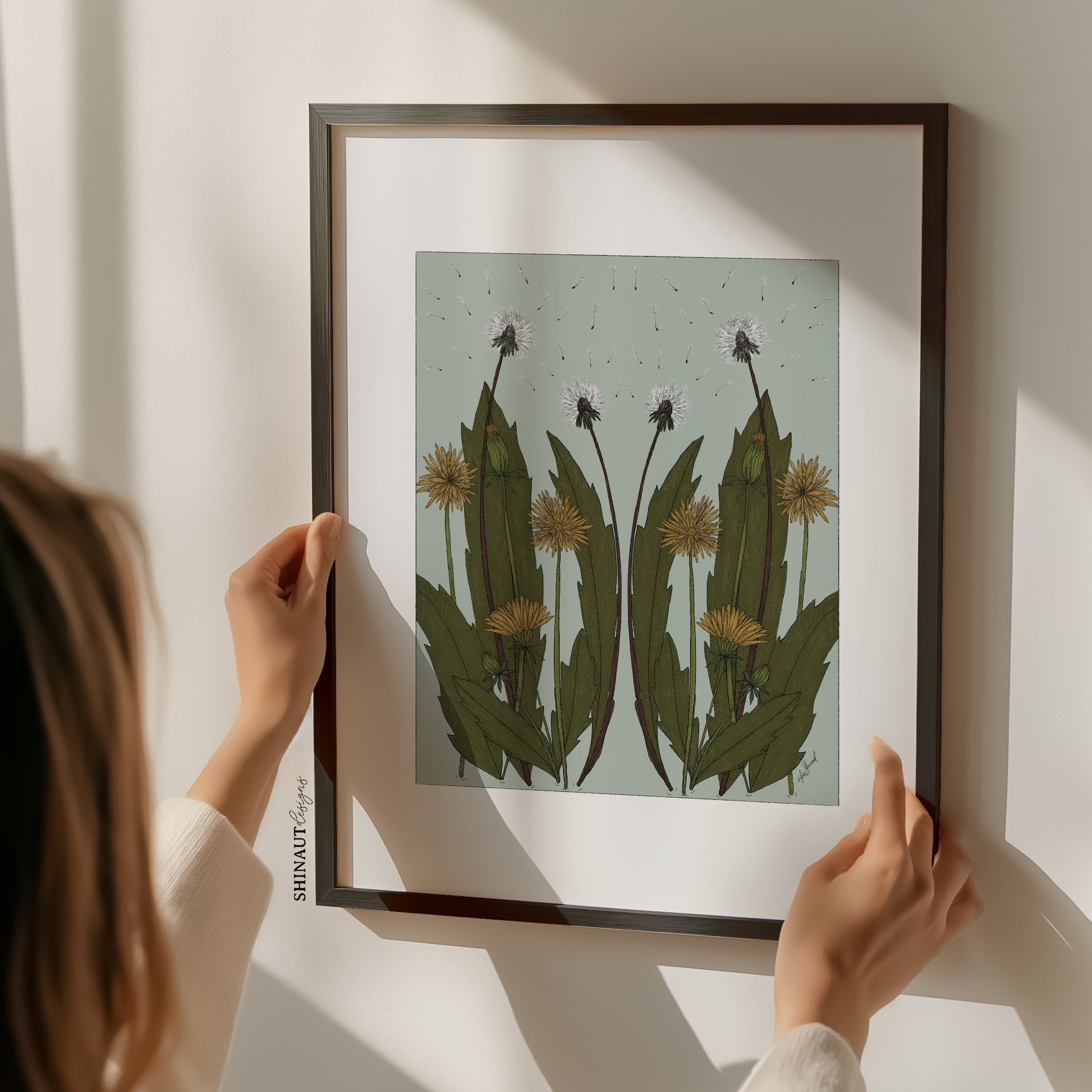 Wild Dandelion Blooms Nouveau Art Print with woman holding print in a black frame on the wall